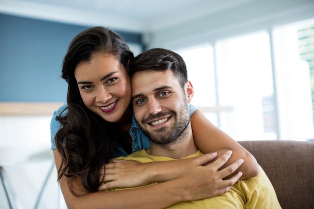 Portrait de couple souriant s'embrassant dans le salon à la maison