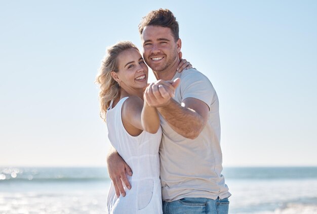 Portrait de couple sourire et câlin sur la plage pour des soins d'amour ou des liens romantiques en plein air Heureux homme et femme souriant dans le bonheur pour les vacances d'été ou la relation amoureuse au bord de l'océan