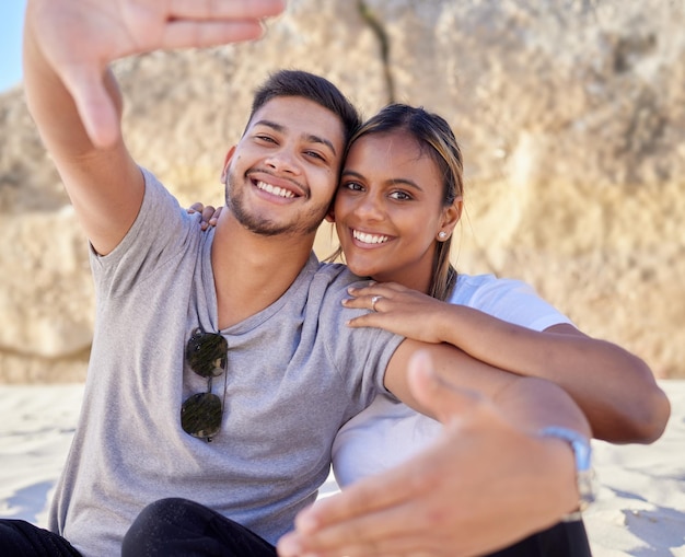 Portrait de couple sourire et selfie sur la plage pour un moment de liaison ou de détente gratuit heureux ensemble à l'extérieur Homme et femme souriant dans le bonheur relationnel pour la capture de photos ou les moments en mer