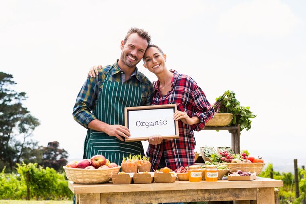 Portrait de couple avec tableau blanc vendant des légumes