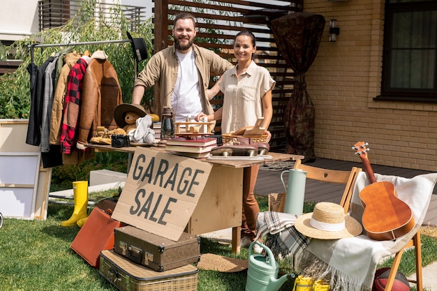 Portrait de couple vendant des trucs de garage dans la cour