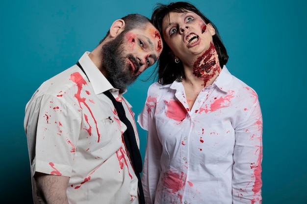 Portrait d'un couple de zombies posant devant la caméra, ayant l'air mort-vivant et effrayant avec des blessures sanglantes ou de vilaines cicatrices. Monstres apocalyptiques avec des rayures sales agissant dangereux et agressifs.