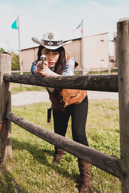 Photo portrait d'une cow-girl tenant un pistolet alors qu'elle se tient au ranch