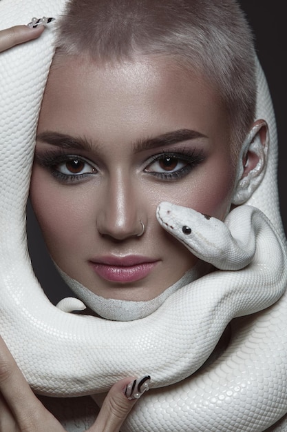 Portrait créatif de beauté d'une fille avec un serpent blanc