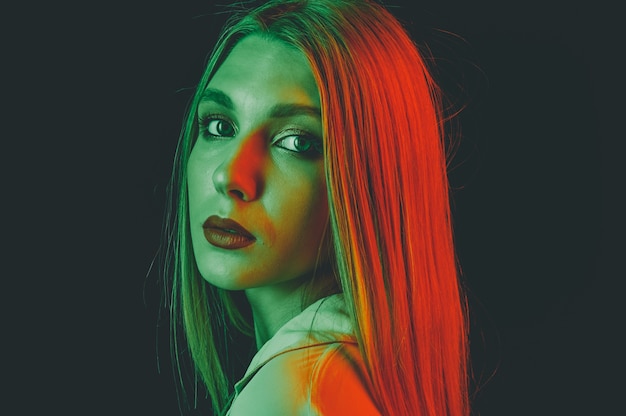 Portrait créatif d'un gros plan beau modèle féminin. éclairage orange et vert dans le studio.