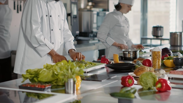 Portrait d'un cuisinier afro-américain en uniforme faisant des préparations de repas dans la cuisine du restaurant. Chef masculin cuisinant un plat gastronomique avec une délicieuse recette de cuisine et de gastronomie. Prise de vue à main levée.