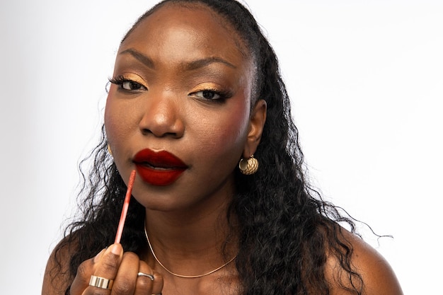 Photo portrait d'une dame afro-américaine avec un maquillage brillant appliquant du rouge à lèvres sur les lèvres concept de beauté