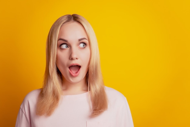 Portrait d'une dame folle et excitée, la bouche ouverte regarde l'espace vide sur fond jaune