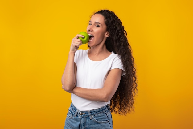 Portrait d'une dame latine souriante tenant une pomme qui mange