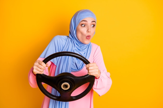 Portrait d'une dame muslimah assez attentive portant le hijab conduisant des lèvres de moue de voiture invisibles façon route déroute isolée sur fond de couleur jaune vif