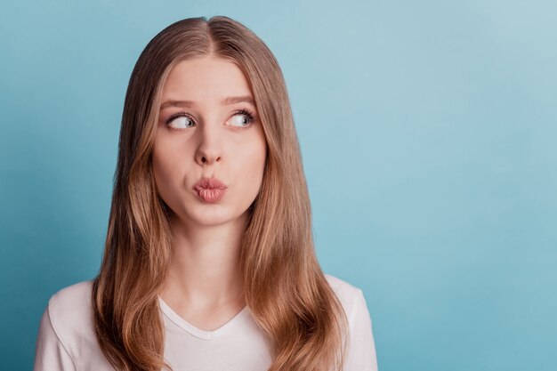 Portrait d'une dame rêveuse romantique regarde l'espace vide côté envoyer un baiser d'air sur fond bleu