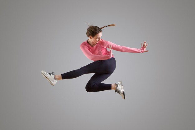 Photo portrait d'une danseuse moderne sautant en l'air sur fond gris