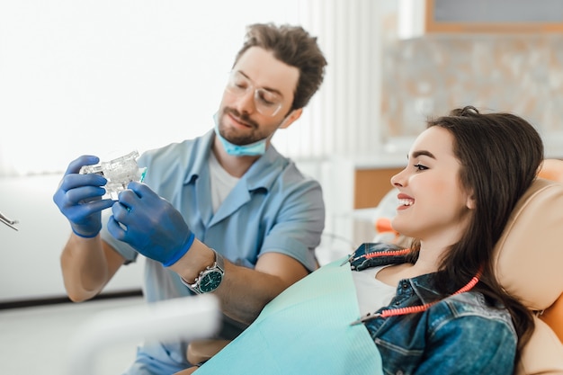 Portrait de dentiste explique au patient sur la disposition des dents conseillant la santé.