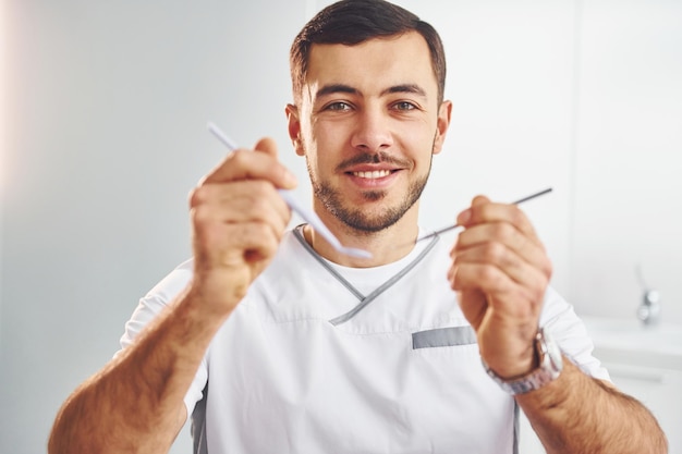 Portrait d'un dentiste professionnel avec un équipement qui se tient à l'intérieur