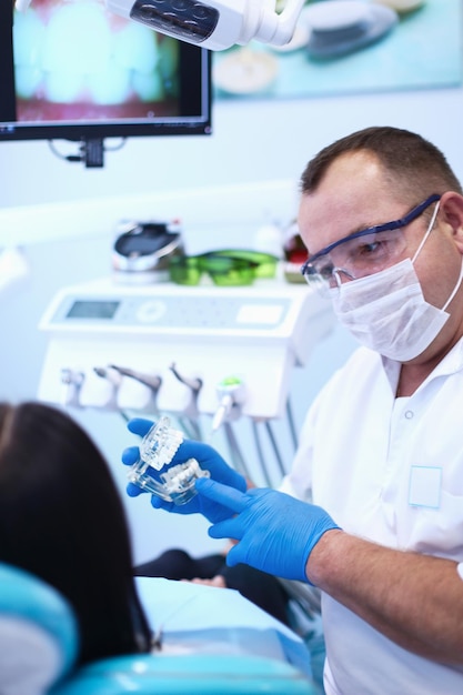 Portrait d'un dentiste qui traite les dents d'une jeune patiente