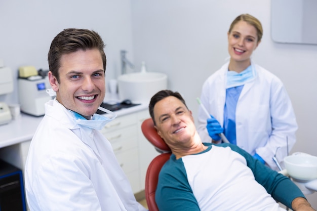 Portrait de dentistes souriants et patient de sexe masculin