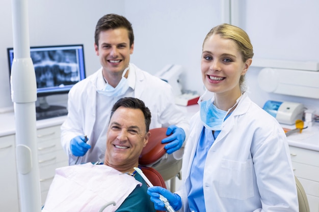 Portrait de dentistes souriants et patient de sexe masculin