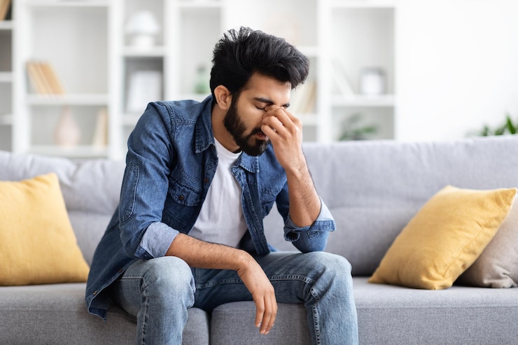 Photo portrait de dépression saisonnière d'un homme indien triste assis sur le canapé à la maison