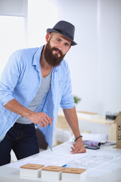 Portrait d'un designer masculin avec des plans au bureau au bureau.