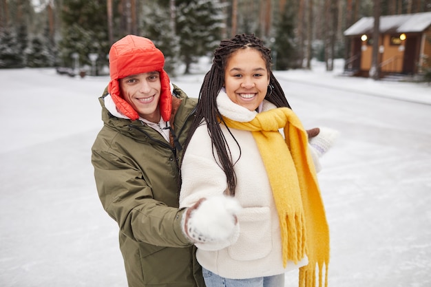 Portrait de deux amis heureux souriant à la caméra tout en se tenant à l'extérieur en journée d'hiver