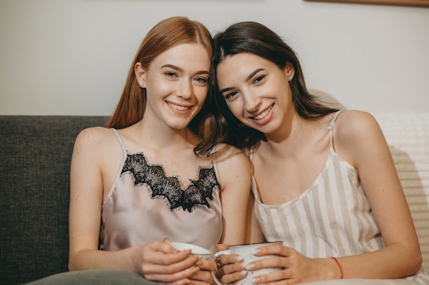 Portrait de deux belle jeune femme buvant du café et s'amusant à se détendre sur le canapé