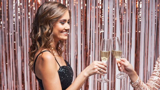 Portrait de deux belles femmes élégantes tinter les verres de champagne.
