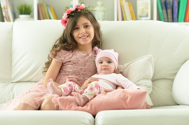 Portrait de deux belles soeurs mignonnes posant dans un canapé à la maison