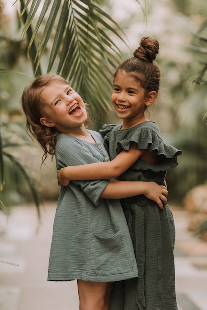 Portrait de deux charmantes filles souriantes appartenant à différentes races entourées de feuilles tropicales
