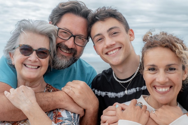 Portrait de deux couples de mères et de fils famille multigénérationnelle smiling at camera embrassant