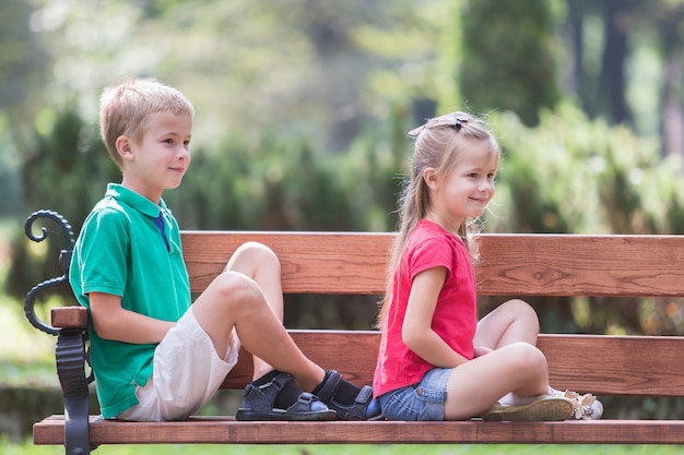 Portrait de deux enfants assez mignon garçon et fille s'amuser sur un banc dans le parc d'été à l'extérieur.