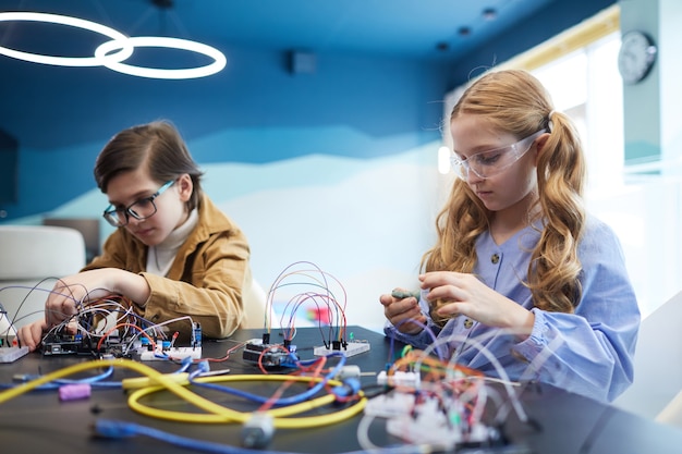 Portrait de deux enfants construisant des robots et expérimentant des circuits électriques en classe d'ingénierie à l'école