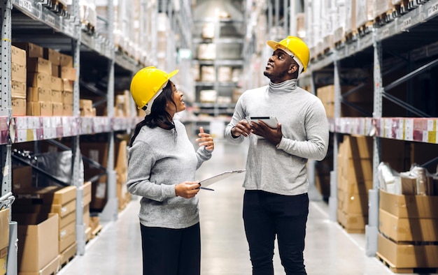 Portrait de deux équipes d'ingénieurs afro-américains expédition des détails de la commande sur tablette vérifier les marchandises et les fournitures sur les étagères avec l'inventaire des marchandises dans l'industrie logistique de l'entrepôt d'usine et l'exportation des entreprises