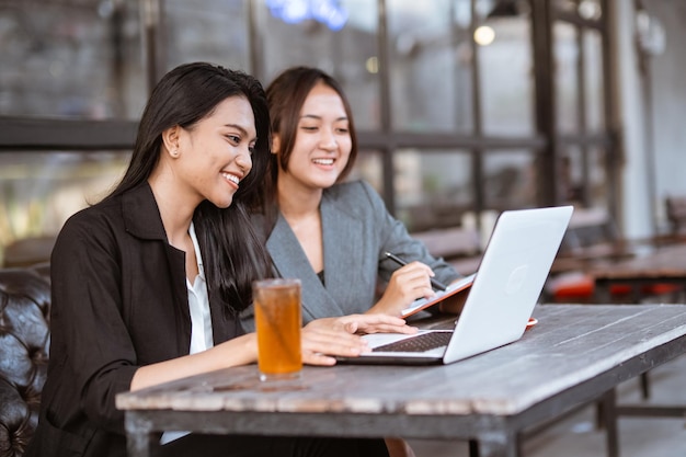 Portrait de deux femmes d'affaires asiatiques parlant tout en dégustant un café et en travaillant