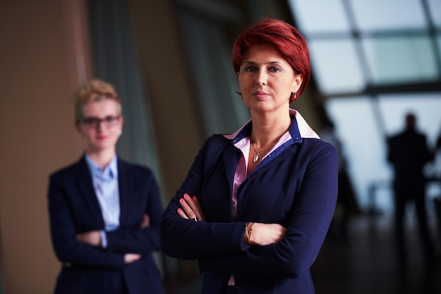 portrait de deux femmes d'affaires à l'intérieur d'un bureau moderne et lumineux, debout dans un groupe en équipe