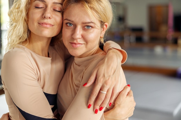 Photo portrait de deux femmes blondes naturelles en vêtements de sport se serrant les coudes tout en posant ensemble après l'entraînement concept de mode de vie sain d'amitié