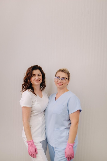 Portrait de deux femmes cosmétologues qualifiées souriant en toute confiance dans un centre médical
