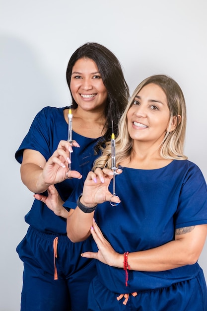 Portrait de deux femmes dentistes souriantes tenant des seringues pour l'anesthésie