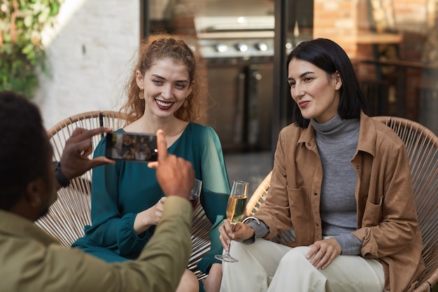 Portrait de deux femmes élégantes posant pour la photo et souriant à la caméra tout en profitant d'une fête en plein air,