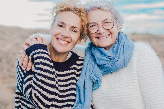 Portrait de deux femmes souriantes, mère senior et fille mature serrant avec amour dans les loisirs en plein air regardant la caméra