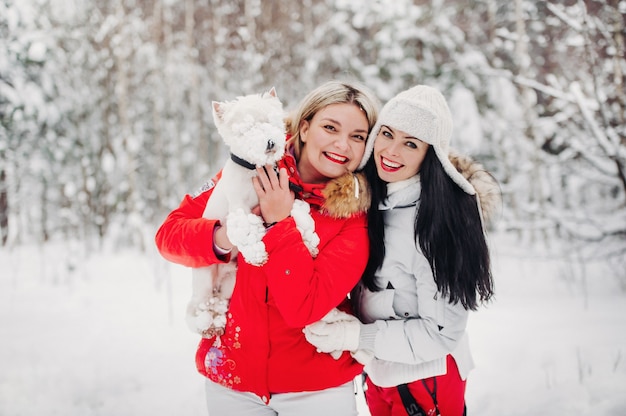 Portrait de deux filles avec un chien dans une forêt froide d'hiver Une fille tient un chien dans ses bras