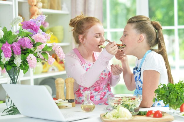 Portrait de deux filles drôles préparant une salade fraîche