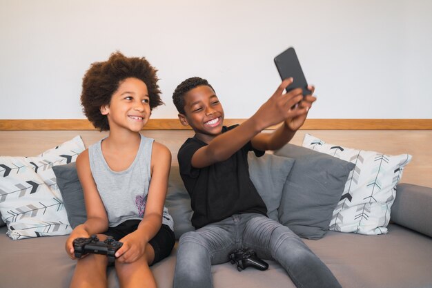 Portrait de deux frères afro-américains prenant un selfie avec un téléphone portable à la maison. Concept de mode de vie et de technologie.