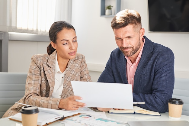 Portrait de deux hommes d'affaires homme et femme regardant des documents lors de la réunion au bureau