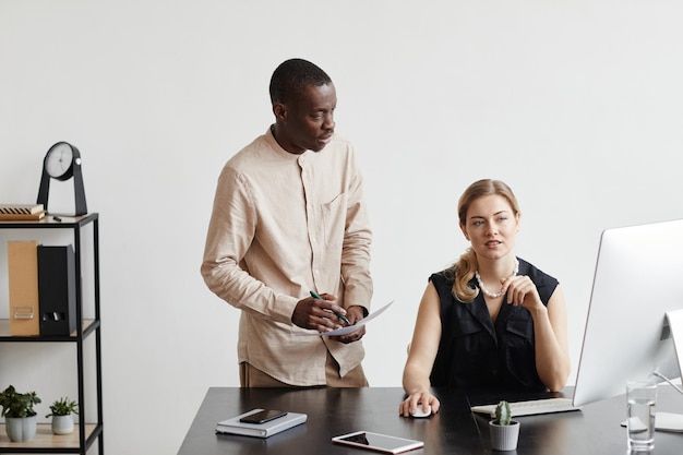 Portrait de deux hommes d'affaires regardant l'ordinateur par bureau dans un espace de copie intérieur de bureau minimal