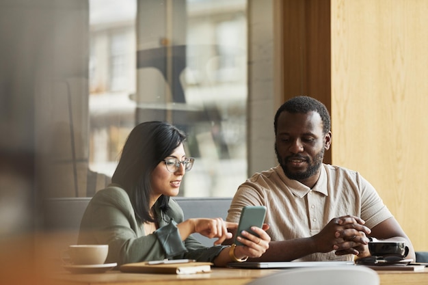 Portrait de deux hommes d'affaires se réunissant à la table du café et regardant l'écran du smartphone, espace de copie