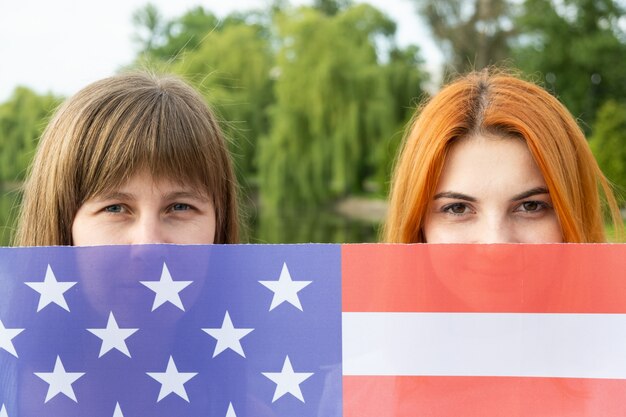 Portrait de deux jeunes femmes cachant leurs visages derrière le drapeau national des USA