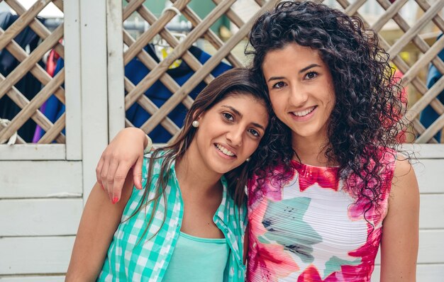 Photo portrait de deux jeunes femmes heureuses à la clôture de jardin blanc