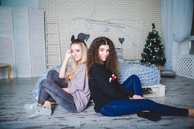 Portrait de deux jeunes femmes près d'un arbre de Noël décoré Nouvel An Une image festive lumineuse de deux sœurs Joyeux Noël