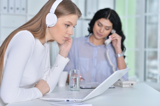 Portrait de deux jeunes femmes travaillant au bureau avec un ordinateur portable