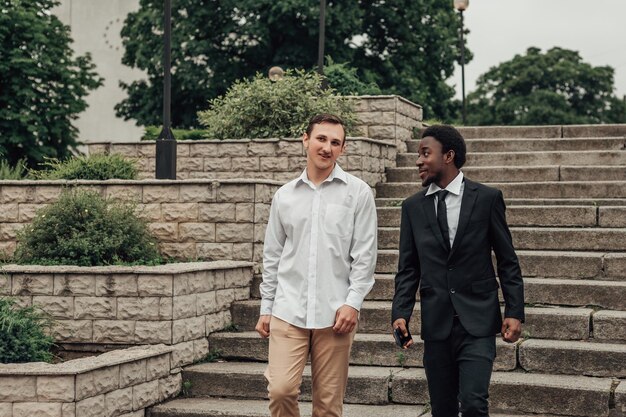 Portrait de deux jeunes hommes d'affaires confiants descendant les escaliers et parlant